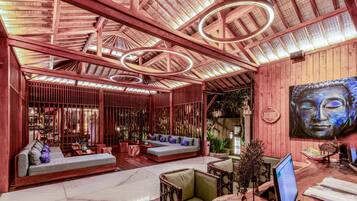 A spacious lobby with a wooden ceiling, a large seating area, and a Buddha painting.