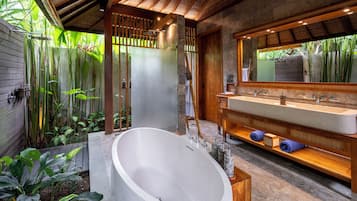 Une salle de bain moderne avec une baignoire sur pieds, un grand miroir et un meuble-lavabo en bois.