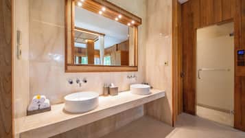 A modern bathroom with two sinks, a large mirror, and a wooden door.