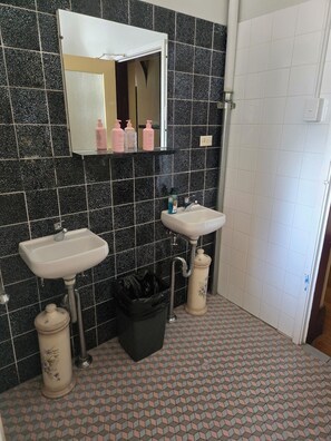 A bathroom with two sinks, a mirror, and a trash bin. - Paxton Hotel (Paxton)