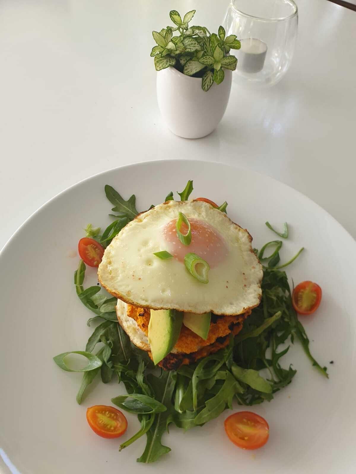 A plate with a sandwich, egg, and greens.