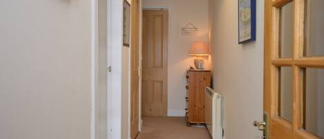 A hallway with a wooden door, a radiator, and a wall-mounted lamp.