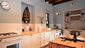 A kitchen with white cabinets, a wooden countertop, a stove, a dishwasher, and a clock on the wall. - Kevington Cottage, charming one bedroom cottage, conservatory, decking area, (Dunoon)