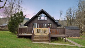 A wooden cabin with a deck, large windows, and a small attached shed. - Iona Lodge, loch views, peaceful location, pet friendly (Taynuilt)