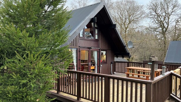 A cabin with a deck, large windows, and a dining area. - Iona Lodge, loch views, peaceful location, pet friendly (Taynuilt)