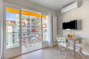 A modern apartment with a balcony, a dining area, and a mounted TV.