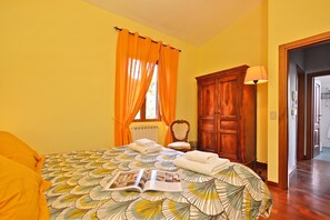 A hotel room with a bed, a wooden wardrobe, a radiator, and a window with orange curtains. - Certosa 4, Firenze, Italy (Firenze)
