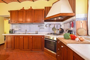 A kitchen with wooden cabinets, a stove, and a variety of kitchen utensils. - Certosa 4, Firenze, Italy (Firenze)