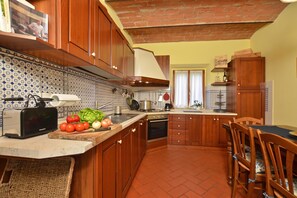 A kitchen with wooden cabinets, a tiled backsplash, and a brick floor. - Certosa 4, Firenze, Italy (Firenze)
