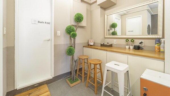 A bathroom with a toilet, a sink, a mirror, and two stools.