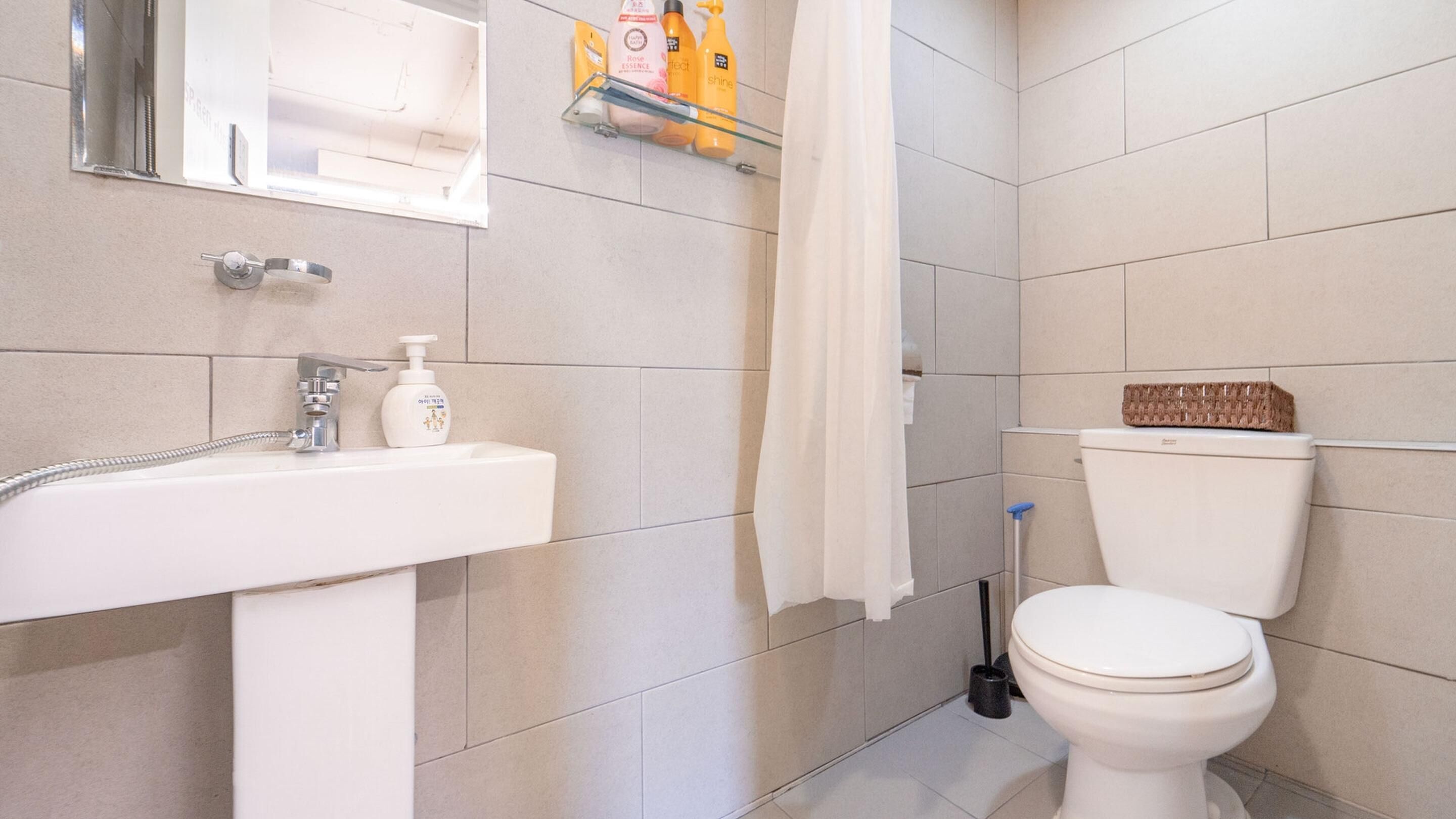 A bathroom with a white sink, toilet, and shower curtain.