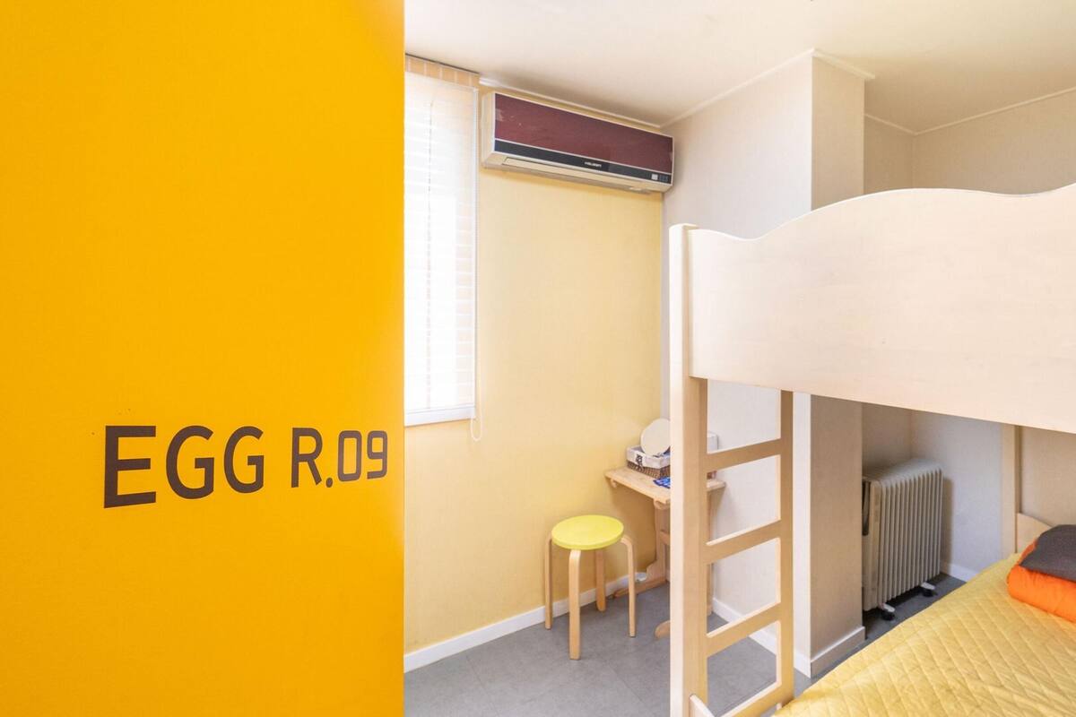 Une chambre d’enfant avec des lits superposés, un bureau et un radiateur.