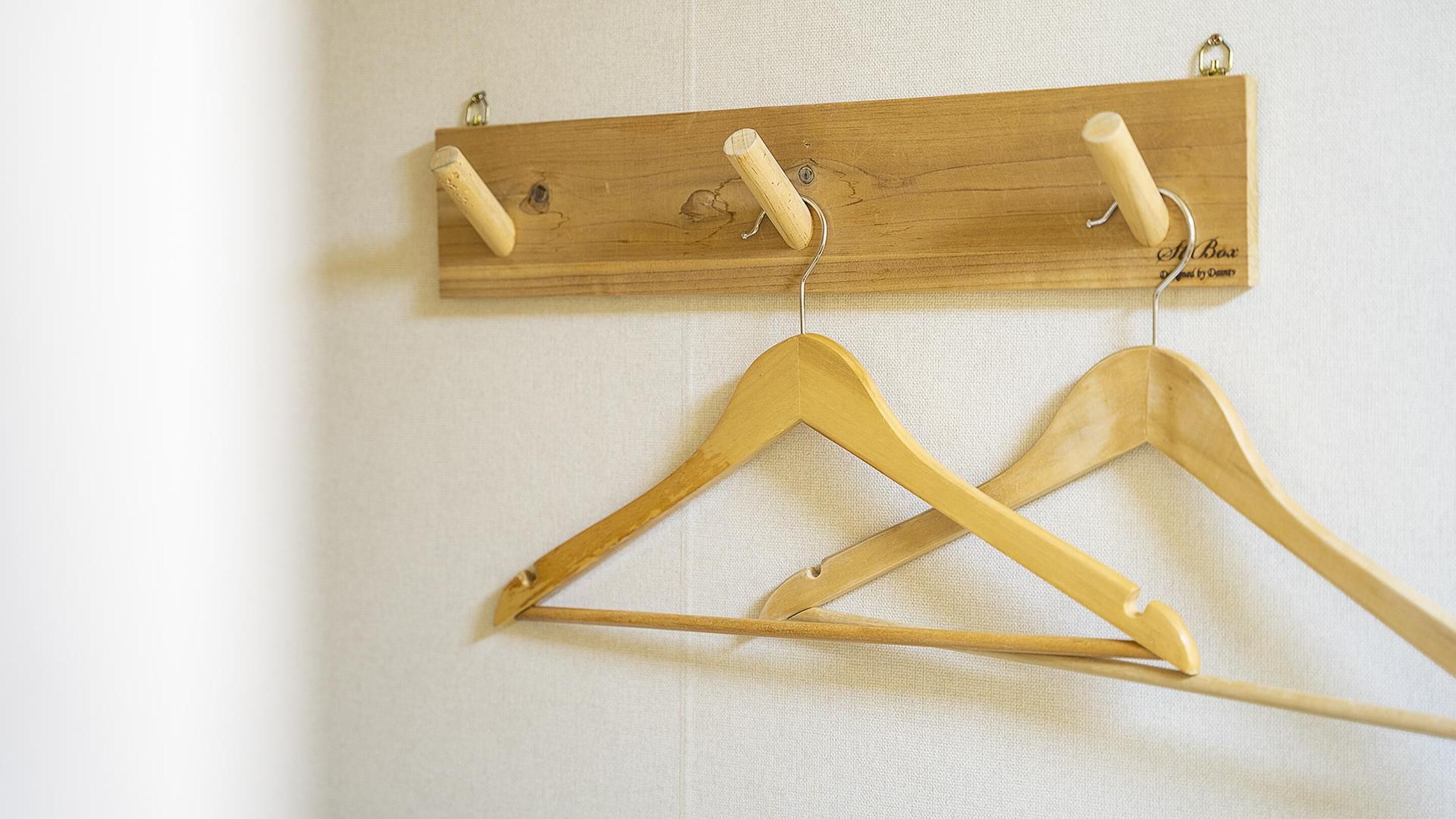 Ein Holz-Kleiderständer mit drei Haken und zwei Holzaufhänger.