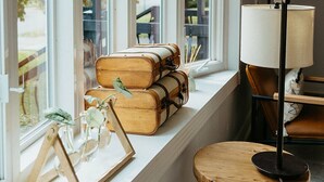 Ein Zimmer mit großen Fenstern, einem Holztisch und einer Lampe.