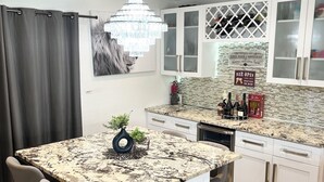 A modern kitchen with a marble countertop, white cabinets, and a chandelier. - FloridaTropical vacation home near the beach, swimming pool with heating system (Pembroke Pines)
