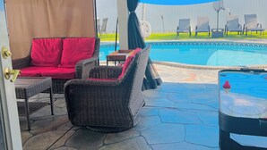A covered patio area with a pool, wicker furniture, and a table with a hockey puck. - FloridaTropical vacation home near the beach, swimming pool with heating system (Pembroke Pines)