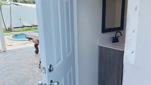 A bathroom with a white door, a sink with a dark countertop, and a mirror above it. - FloridaTropical vacation home near the beach, swimming pool with heating system (Pembroke Pines)