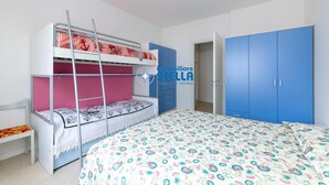 Een stapelbed met een ladder, een enkel bed met een bloemenbedekking en een blauwe garderobe met een deur.