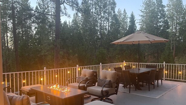 Une terrasse extérieure avec un foyer, des sièges et un parasol.