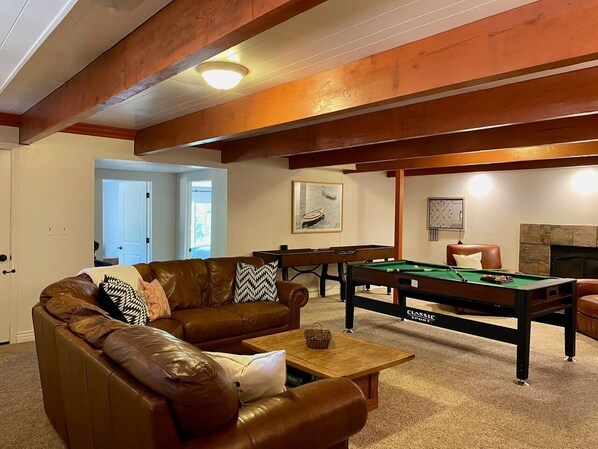 A cozy living room with a brown leather sofa, a pool table, and a fireplace. - Rozoff Retreat (Groveland)