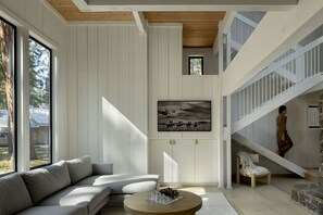 Relax in a spacious room with a comfortable sofa, wooden coffee table, and a staircase leading to an upper level.