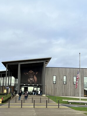Un edificio con un gran mural de una vaca en la fachada, una bandera estadounidense y un grupo de personas entrando.