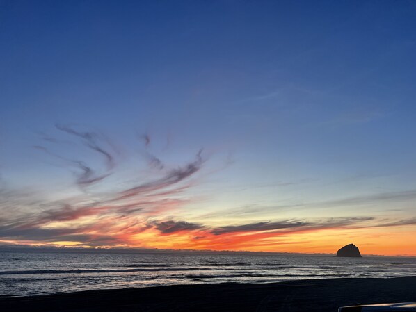 A sunset over the ocean with a silhouette of a landmass.