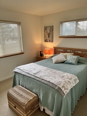 Un dormitorio con cama, lámpara de noche y un cuadro en la pared.