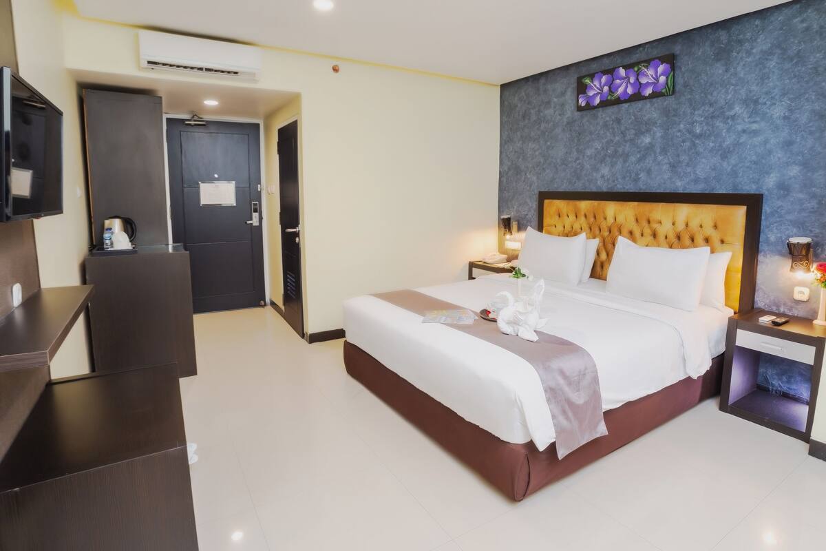 Hotelkamer met een groot bed, nachtkastjes, een flatscreen-tv en een deur naar de badkamer.