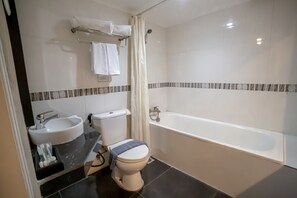 Een badkamer met een bad, toilet, wastafel en douchegordijn.