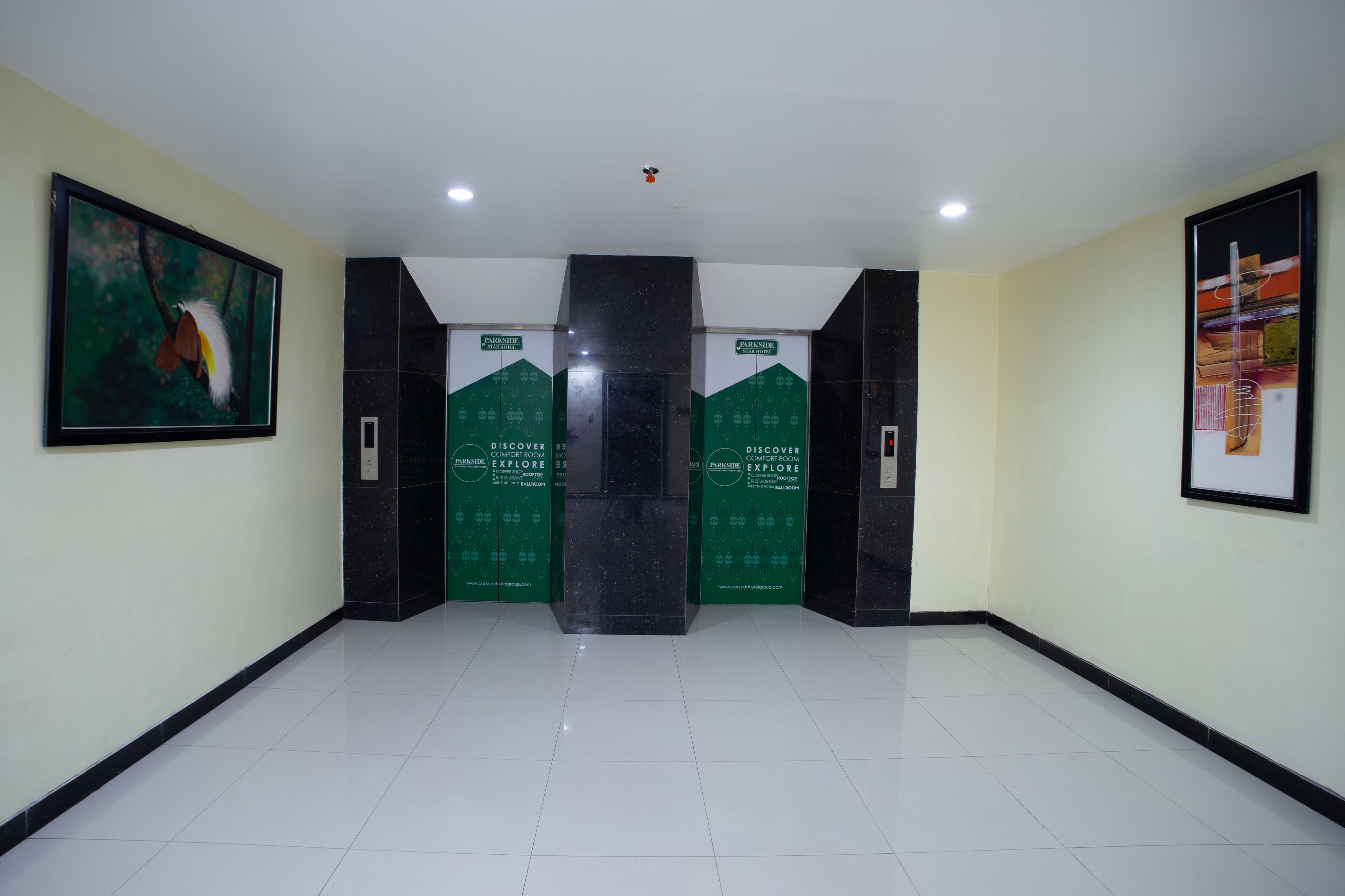 A hallway with a white tiled floor, green and black doors with 'PARKSIDE' signage, and framed artwork on the walls.