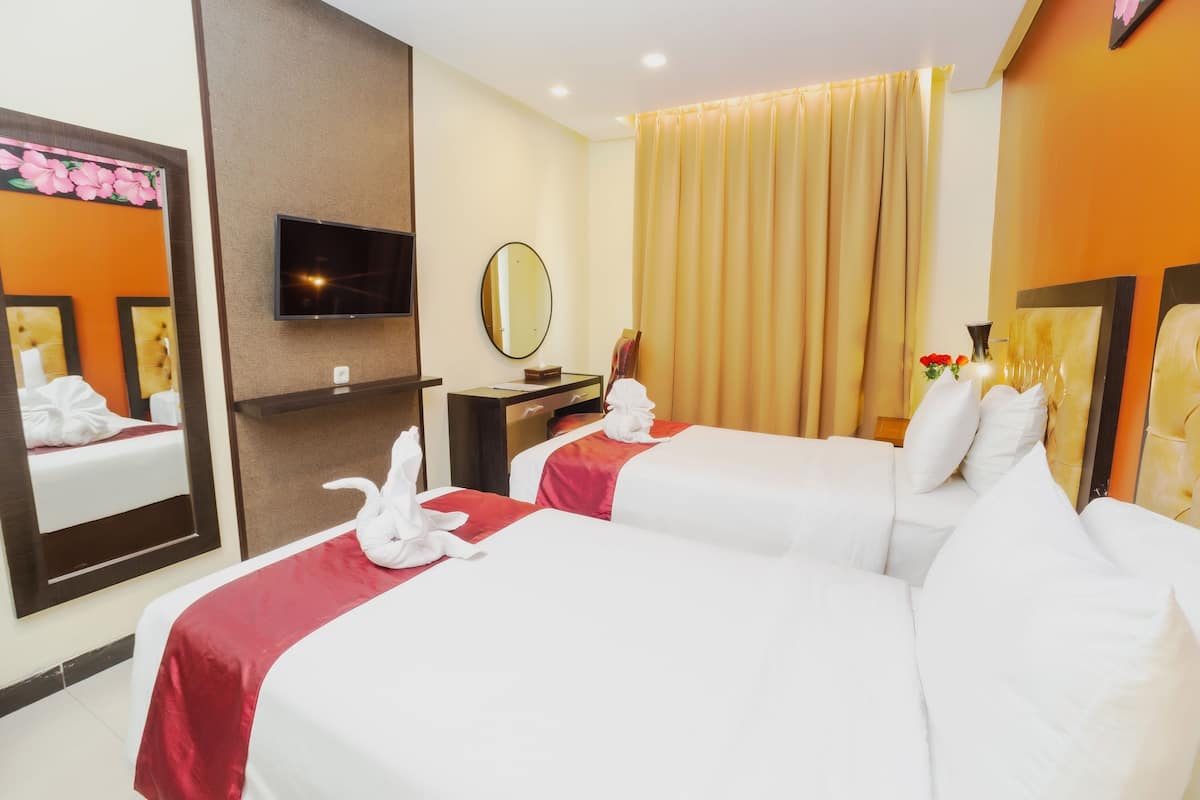 Een hotelkamer met twee bedden, een televisie, een spiegel en een raam met gordijnen.