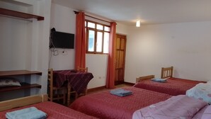 A room with two beds, a desk, and a TV.