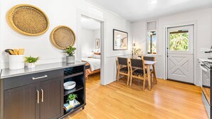 Uma cozinha moderna com piso de madeira, armários escuros e uma área de refeições com mesa e cadeiras.