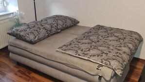 A compact bed with patterned bedding in a room with wooden flooring and a radiator. - Modernized apartment, centrally located in historic old town (Mücheln (Geiseltal))