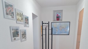 A narrow hallway with a black bench, a map on the wall, and several framed pictures. - Modernized apartment, centrally located in historic old town (Mücheln (Geiseltal))