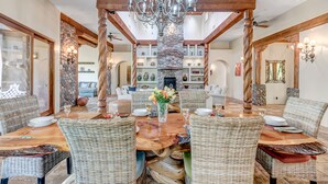 A dining area with a large wooden table, wicker chairs, and a chandelier. - Experience luxury at Sedona Cathedral Shangri-La, a spacious 5-bedroom retreat in the Chapel Area. (Sedona)