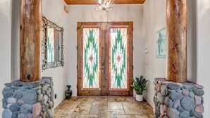 A wooden interior with a stone wall, a chandelier, and a door with stained glass. - Experience luxury at Sedona Cathedral Shangri-La, a spacious 5-bedroom retreat in the Chapel Area. (Sedona)