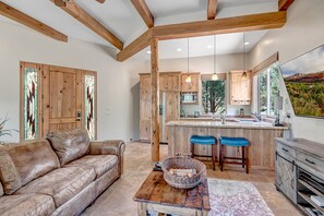 A spacious living room with a leather sofa, a wooden coffee table, and a large window.