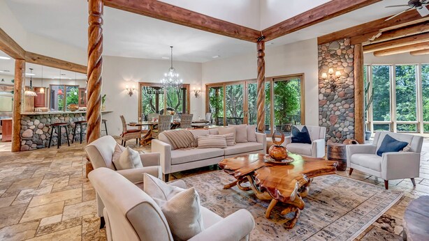 A spacious living room with a large wooden coffee table, comfortable seating, and a stone wall. - Experience luxury at Sedona Cathedral Shangri-La, a spacious 5-bedroom retreat in the Chapel Area. (Sedona)