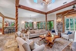 A spacious living room with a large wooden coffee table, comfortable seating, and a stone wall.