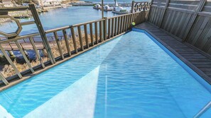 A swimming pool with a wooden deck and a view of a marina.