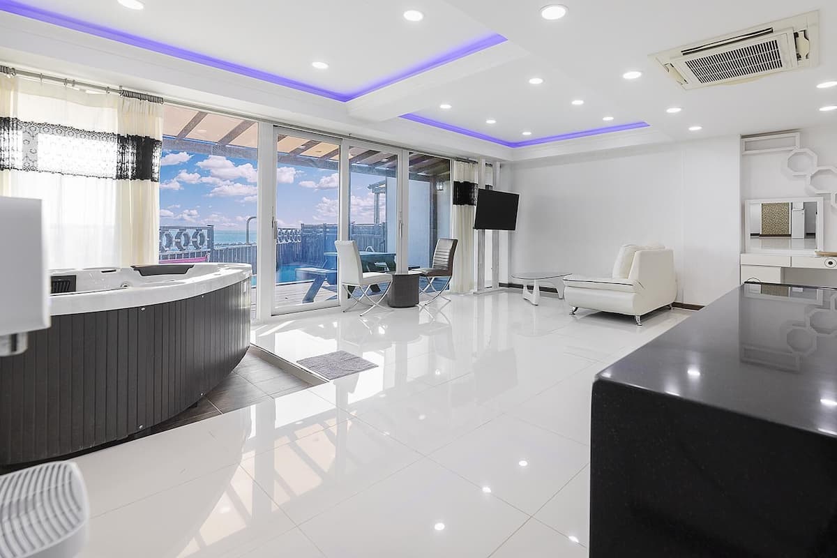 A modern reception area with a glass wall, a reception desk, a seating area, and a large flat-screen TV.