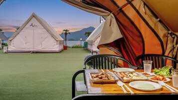 A dining table set with food and a tent in the background.
