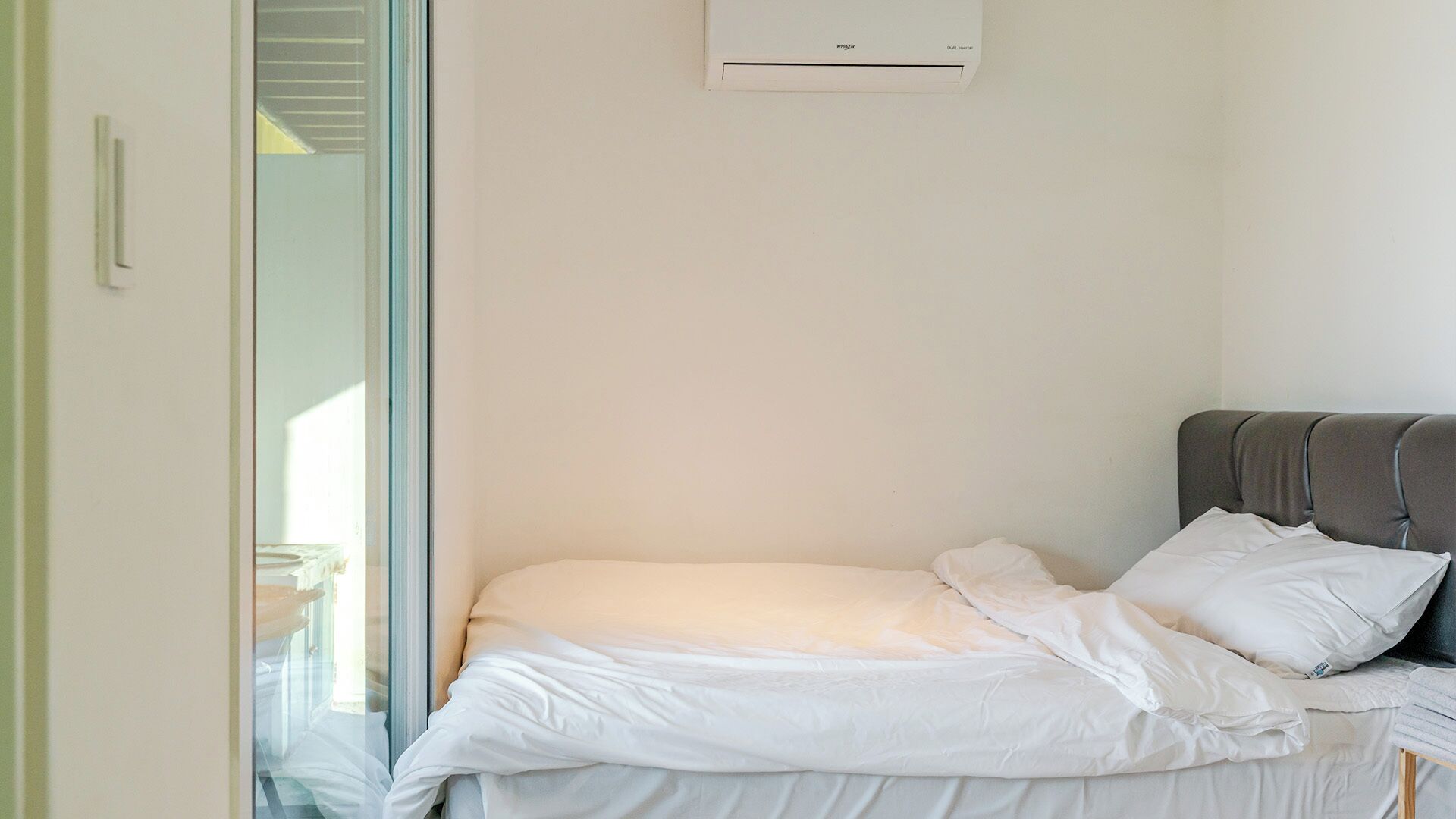 A bedroom with a bed, a window, and an air conditioning unit.