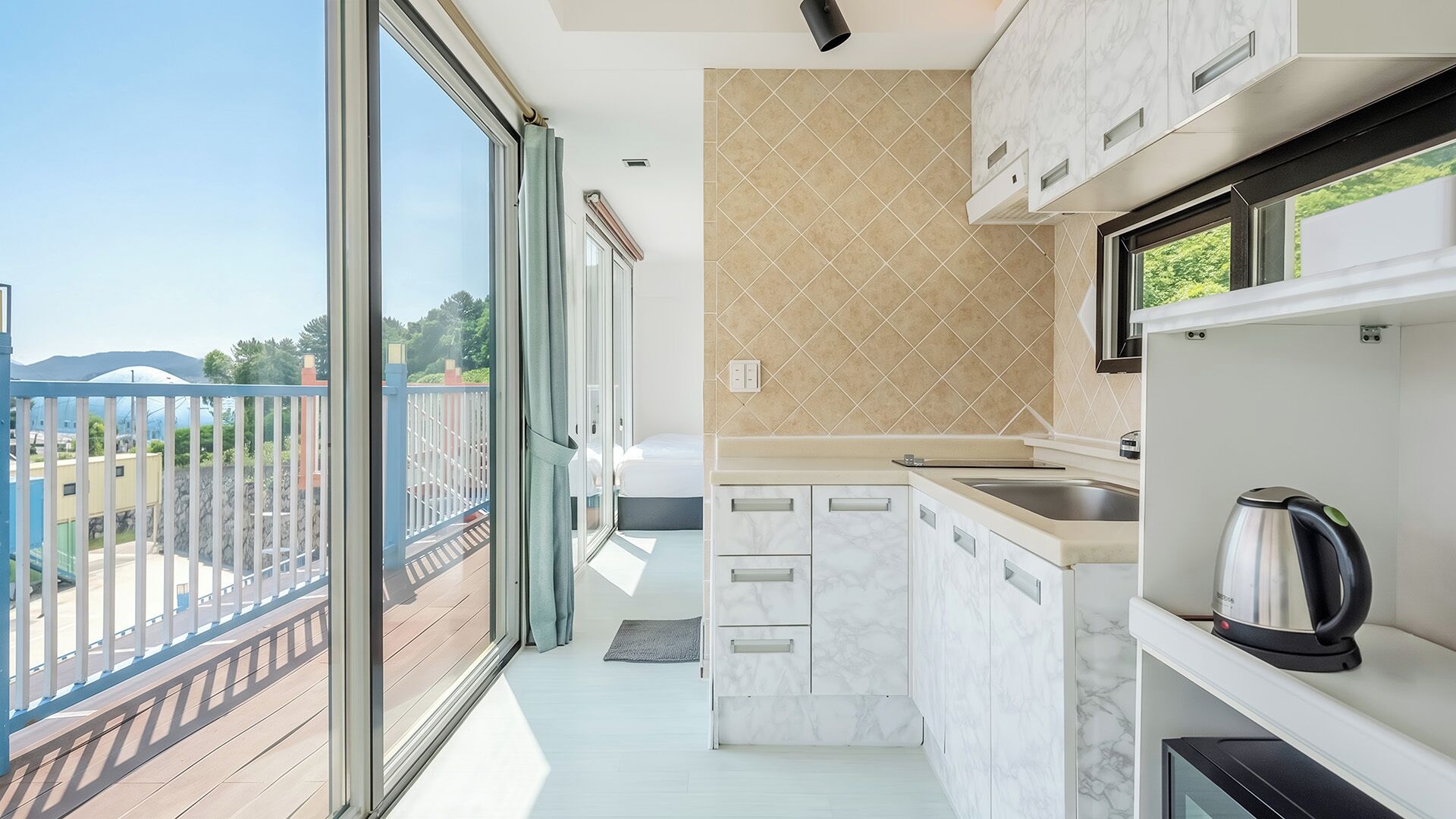 Een moderne keuken met een groot raam, een balkon en uitzicht op groen.
