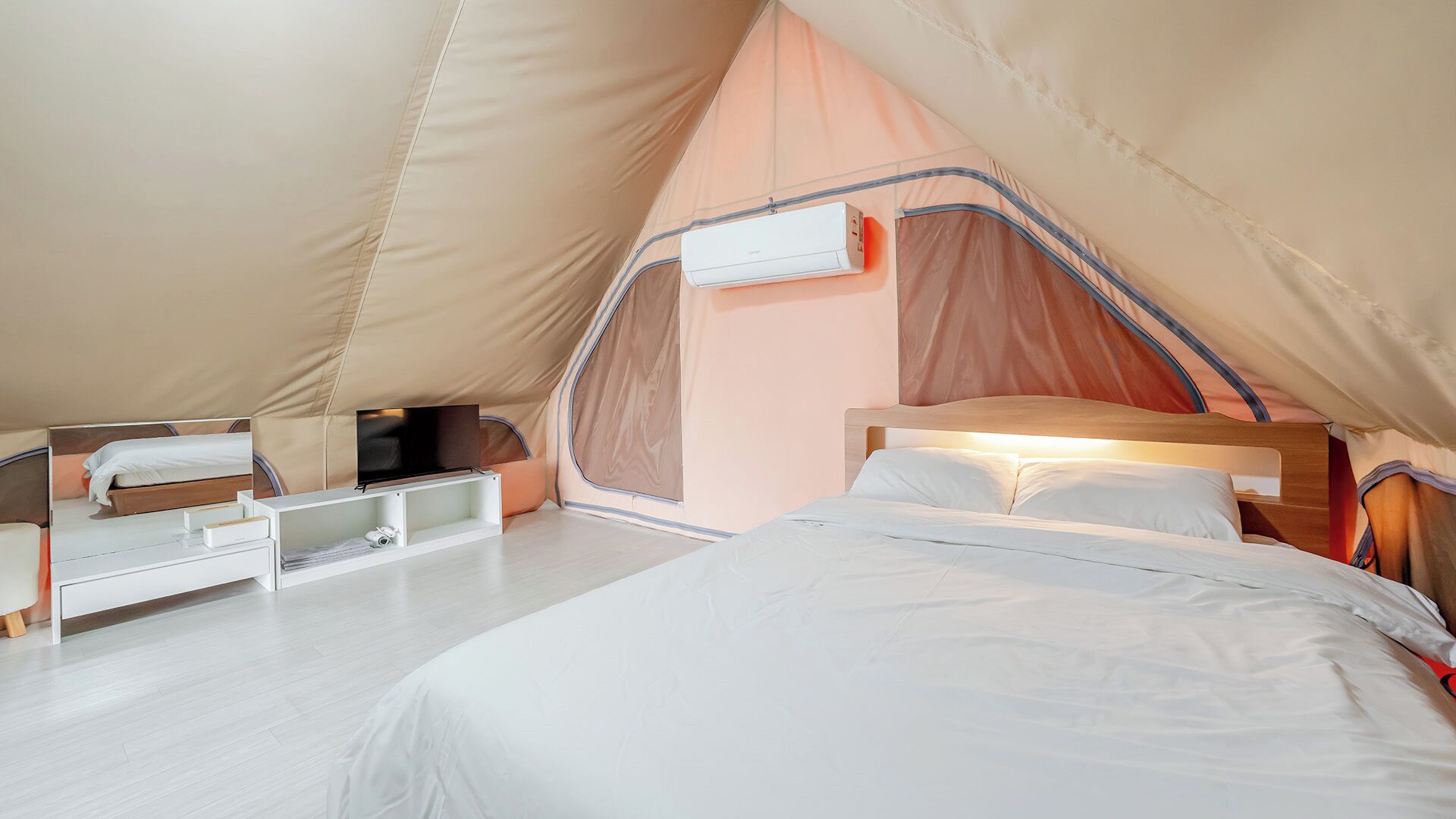 Een tent met een bed, een tafeltje en een plank.