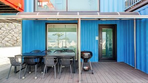 Un patio al aire libre con mesa y sillas, una parrilla y una puerta con un letrero con número.