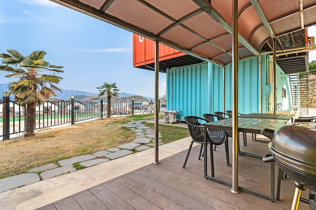 Une terrasse extérieure équipée d’un barbecue, de chaises et offrant une vue sur les montagnes.