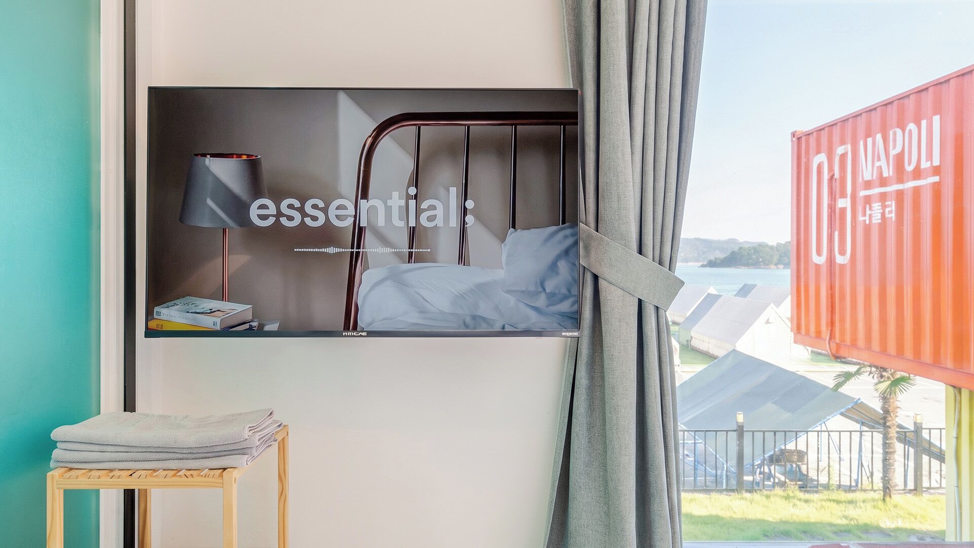 Une chambre avec un lit, une table de chevet avec une lampe et une vue sur une étendue d’eau par la fenêtre.